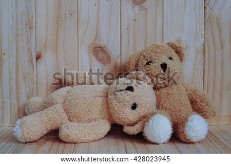 Two teddy bears sitting together on wooden background. Snuggle. Friendship concept. Love concept. Greeting card on wood.