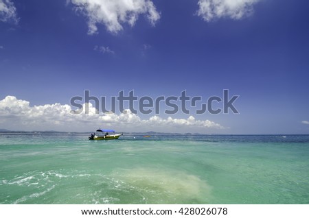 scenic sea view of the Kapas Island (Cotton Island) at Terengganu, Malaysia. Clear water and blue sky background.fiber boat anchored