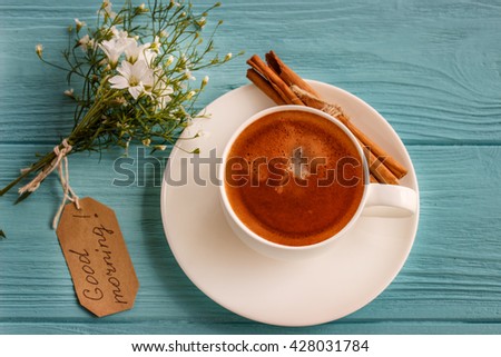 
Coffee mug with white flowers and notes good morning on blue rustic table from above, breakfast 