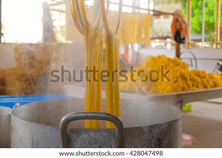 a selective focus picture of boiling raw silk worm thread over pot 