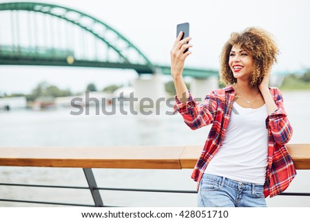 Young woman standing at the balcony and taking selfie