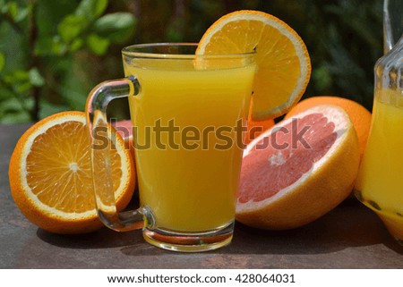 The glass of fresh fruit  juice and citrus fruits cut in half. 