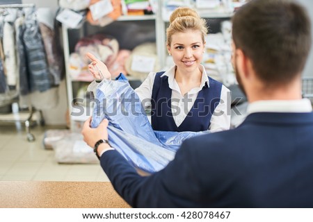 Girl worker Laundry man gives the client clean clothes at the dry cleaners Royalty-Free Stock Photo #428078467