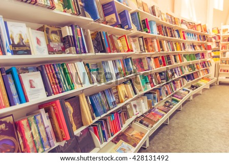 Rows of different colorful books lying on the shelves in the modern urban bookshop Royalty-Free Stock Photo #428131492