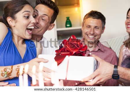 pretty girl with birthday cake receiving the gift from his friends