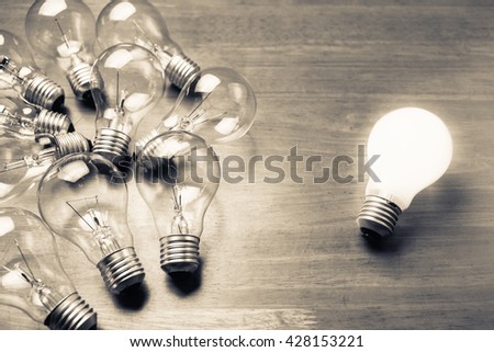 White light bulb glowing separate from others Royalty-Free Stock Photo #428153221