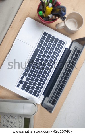laptop with pen holder  empty mug and phone