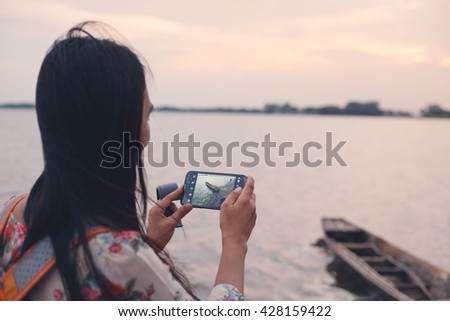 woman taking a photo wood boat with her phone