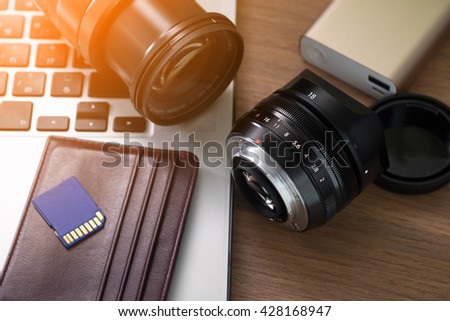 Photographer studio, camera lens, sd cards, power bank, laptop on table. 