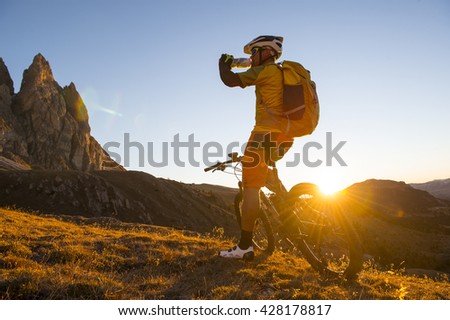 Sportsman drinking energy drink before the ultimate circuit trail at sunset super for the downhill