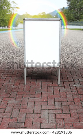 A blank advertisement A-board with rainbow flare in a green park for the concept: Nature's sign.