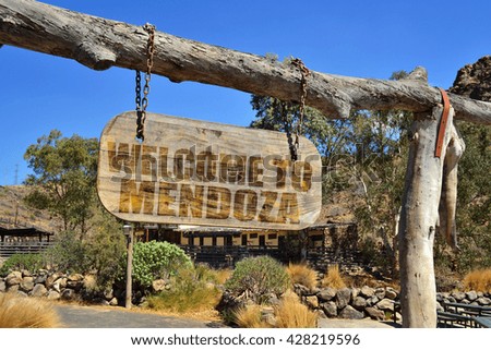 old vintage wood signboard with text " welcome to Mendoza" hanging on a branch