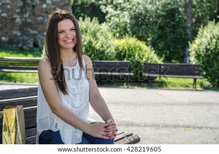 Girl or teenager sitting on a park bench with a gold bag