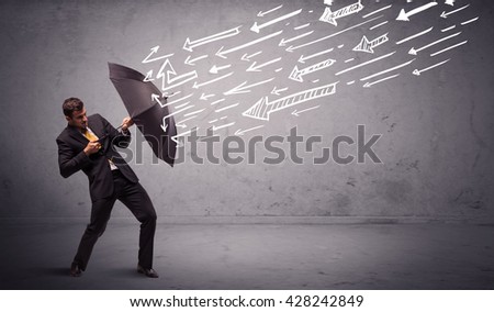 Business man standing with umbrella and drawn arrows hitting him on grungy background