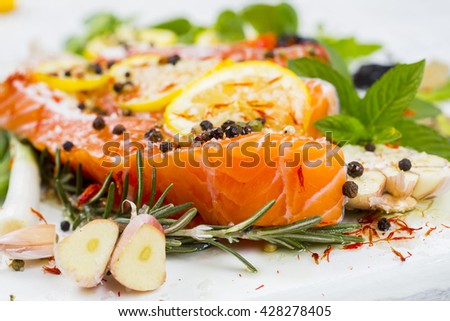 Raw salmon steak on a light wooden background. Ingredients for cooking: vegetables, spice and lemon. Rustic style. Top view. Selective focus