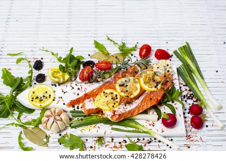 Raw salmon steak on a light wooden background. Ingredients for cooking: vegetables, spice and lemon. Rustic style. Top view. Selective focus
