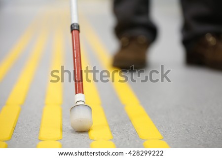Blind pedestrian walking and detecting markings on tactile paving with textured ground surface indicators for blind and visually impaired. Blindness aid, visual impairment, independent life concept.
 Royalty-Free Stock Photo #428299222