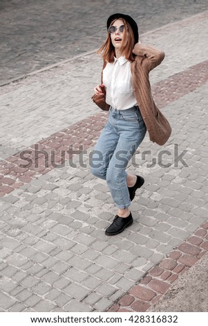 Beautiful girl in a hat and sunglasses walking on the pavement