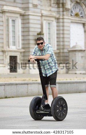 young happy tourist man riding city tour segway driving happy and excited visiting Madrid palace in Spain having fun in urban transport concept