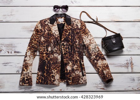 Leopard blazer and black purse. Sunglasses and vintage bag. Luxury clothing item on display. Designer clothes at special price.