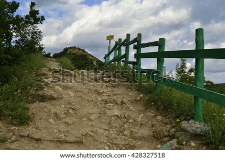 Trail  with wooden fence and tourist sign to Bulgarian nature landmark pyramids of Stob 