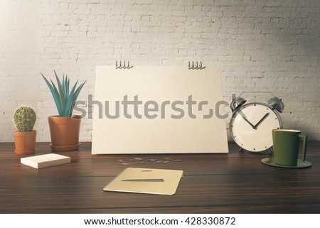 Closeup of office table with blank card, plants, coffee cup, alarm clock and stationery items on white brick background. Mock up, 3D Rendering