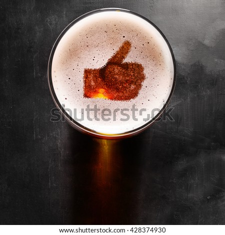loving beer, thumb symbol on foam in glass on black table, view from above Royalty-Free Stock Photo #428374930