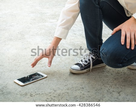 Person Picking Broken Smart Phone (Cracked Screen) of the Ground Royalty-Free Stock Photo #428386546