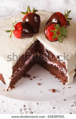 Beautiful chocolate cake with white icing and strawberries close-up on a dish. vertical
