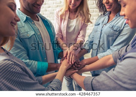 Cropped image of young people of different nationalities holding hands together and smiling