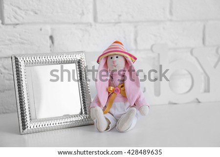 Toy rabbit with frame on white wall background