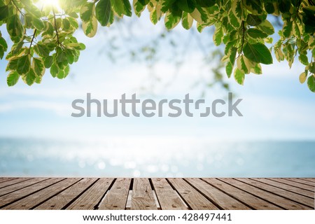 Wooden houses by the sea Wood table top with blurred nature scene tropical beach and blue sky, holiday background concept - can be used for display or montage your products.