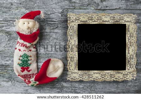 Santa Christmas sock on rustic wooden background with vintage photo frame