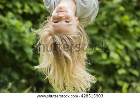 Portrait of Happy little blond girl playing on a rope web playground outdoor. Upside down
 Royalty-Free Stock Photo #428515903