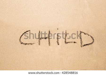 written word CHILD on sand of beach