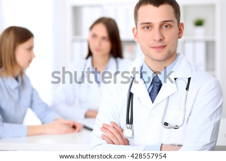 Friendly male doctor  on the background with patient  in hospital. High level and quality medical service concept.  