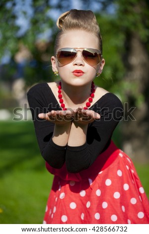 Pin-Up. Lovely little girl in the retro red dress in summer park