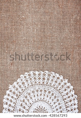 Vintage background with lace on the old rude burlap