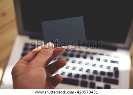 Photo Man Showing Blank Black Business Card and Using Modern Laptop Blurred Background. Mockup Ready for Private Information. Sunlight Reflections Surface Gadget. Horizontal mockup