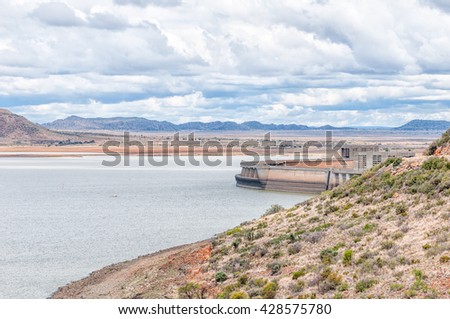 The wall of the Gariep Dam on the border between the Free State and Northern Cape provinces. It is the largest dam in South Africa. The dam is half full Royalty-Free Stock Photo #428575780