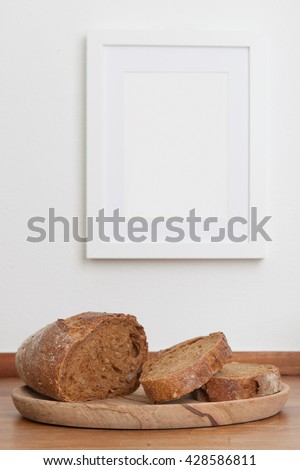 Bread on table, empty picture frame on wall, in background, stock picture