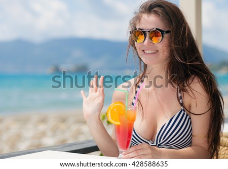 Happy woman with cocktail in the beach bar during tropical vacation