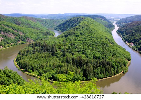 Saarschleife - The Saar river turning around the hill in Mettlach, Saarland, Germany. View of the Saar river bend from the vantage point Cloef. Beautiful trip destination on summer day. Royalty-Free Stock Photo #428616727