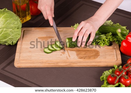 Cucumber cutting with the knife - salad prepearing. Close up photo.