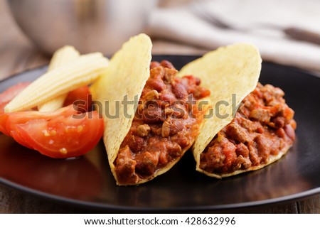 Tacos with chili con carne, tomato, and pickled baby corns