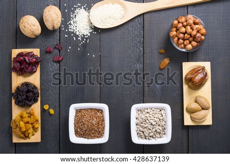 sun dried super foods, nuts and seeds, frame on black wood table background