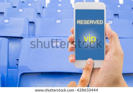 man holding a phone in a stadium and reserving a seat with a smart phone on line