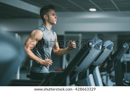 Young man in sportswear running on treadmill at gym Royalty-Free Stock Photo #428663329