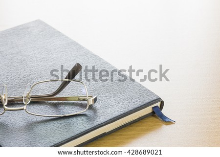 Glasses put on a text book on wood desk background
