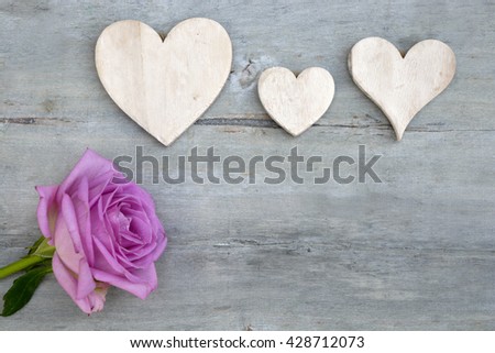 Pink purple rose on a grey old wooden background with white wash heart shape tags with empty copy space